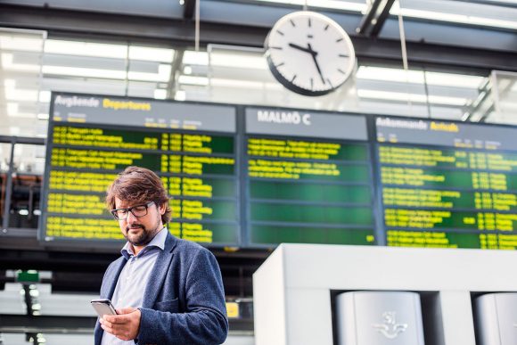 man framför avgångstavlan på en tågstation